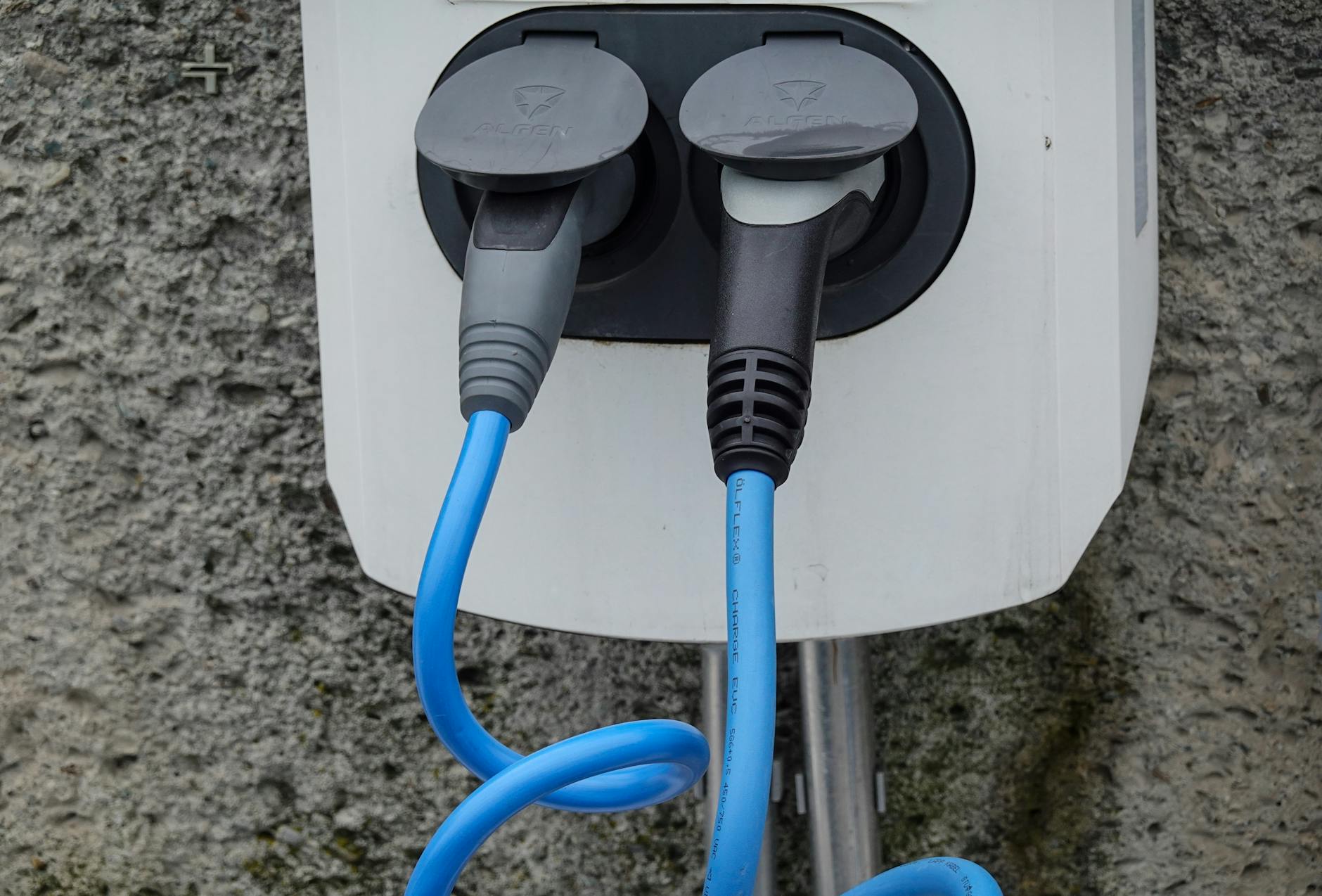 Electric vehicle charging station with two cables plugged in, showing public charging infrastructure