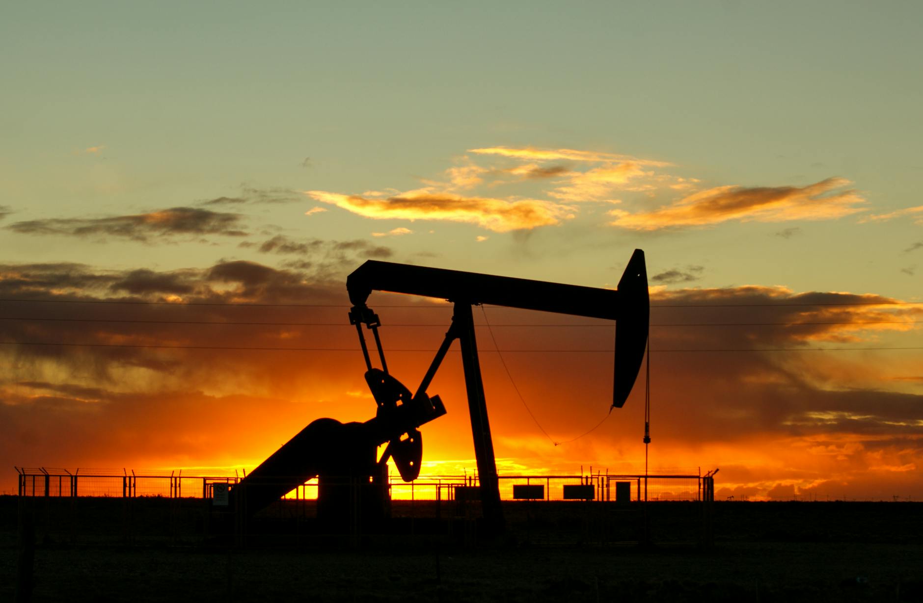 Oil pump jack working in an open field at dusk