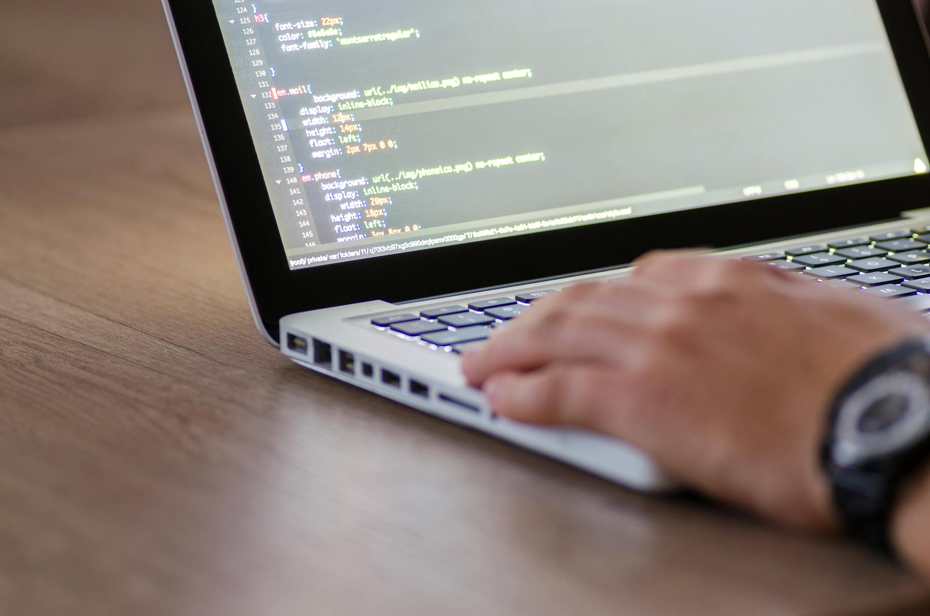 A laptop open on a code editor in a dimly lit workspace