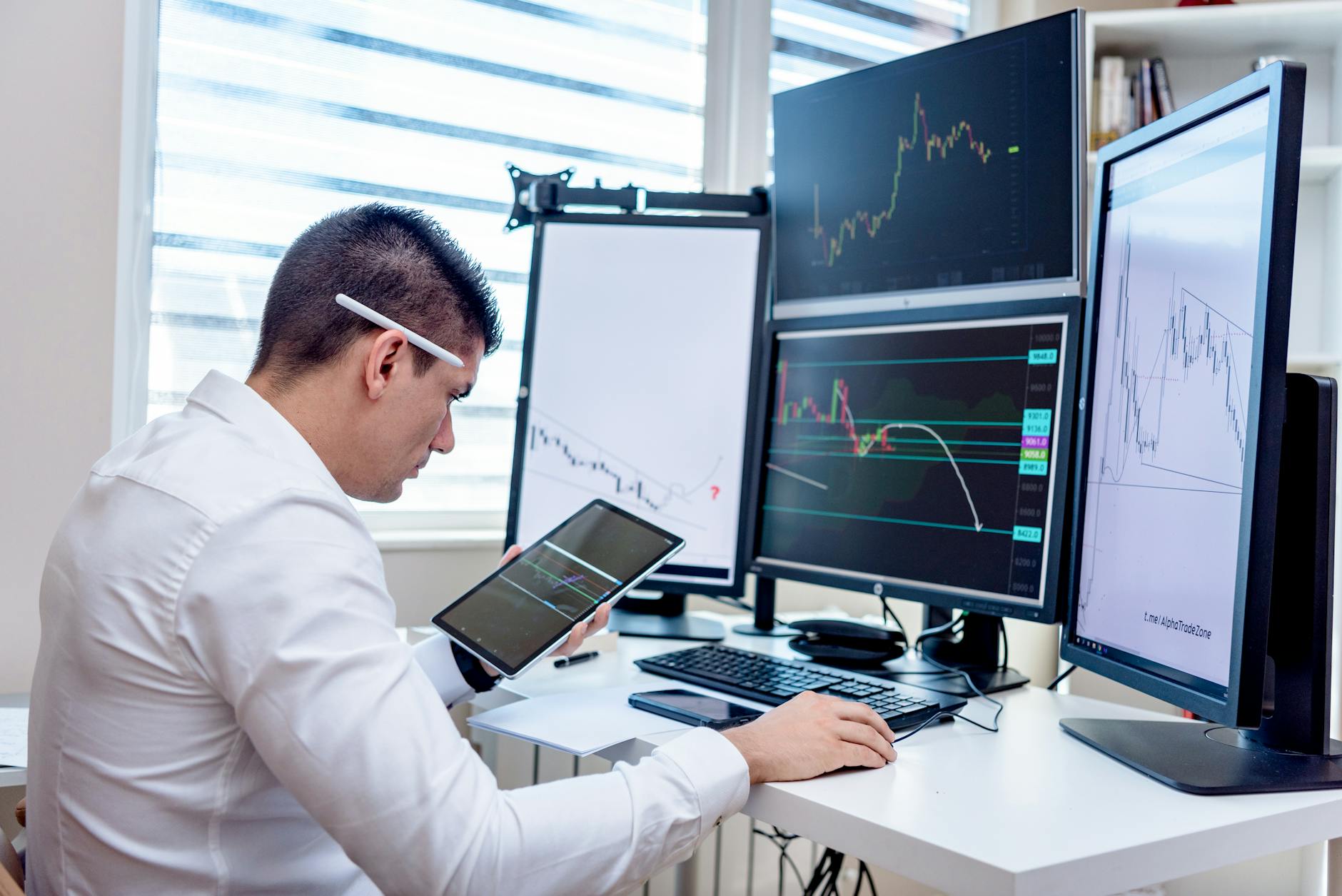 Professional analyzing stock market graphs on multiple monitors at work desk