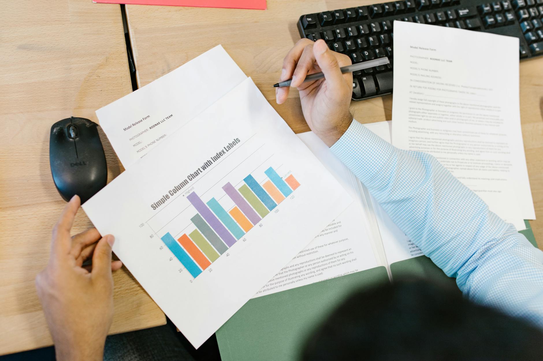 Analyst reviewing a printed bar chart and company documents at a desk