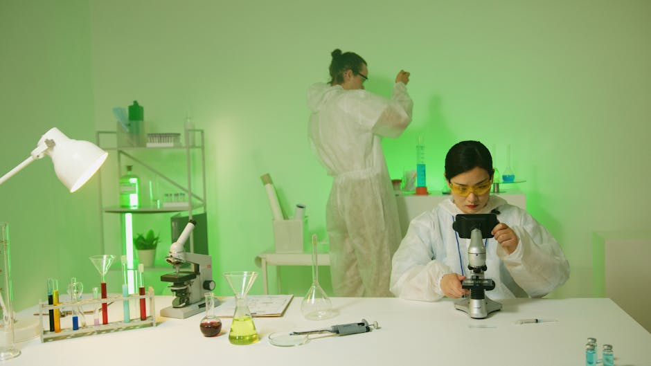 Scientists in protective suits working with a microscope in a biotech lab