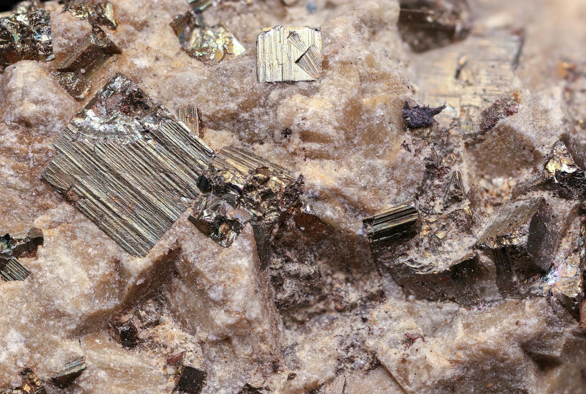 Pyrite crystals embedded in rough rock surface, illustrating mineral deposits found in exploration drilling