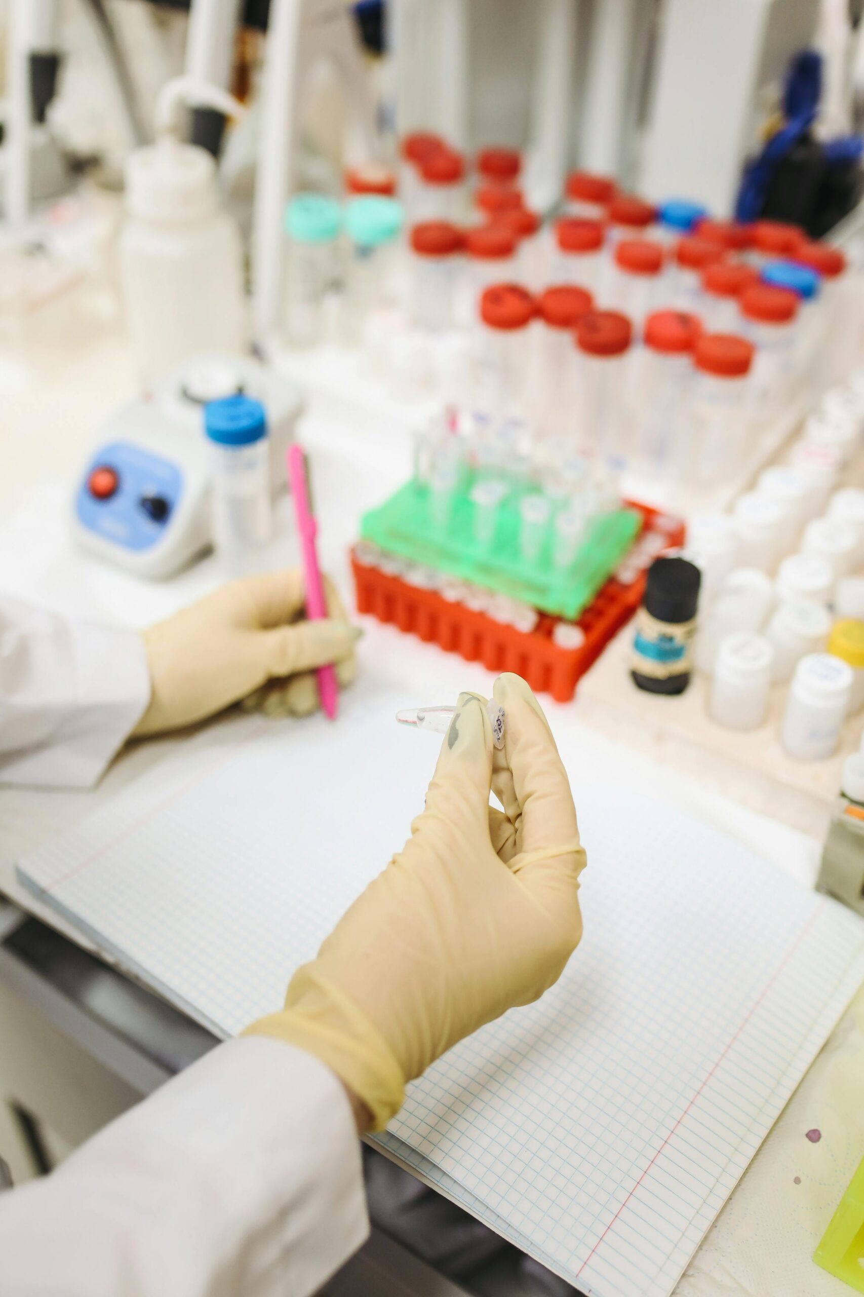 Lab technician handling test tubes and notes in a biotech laboratory