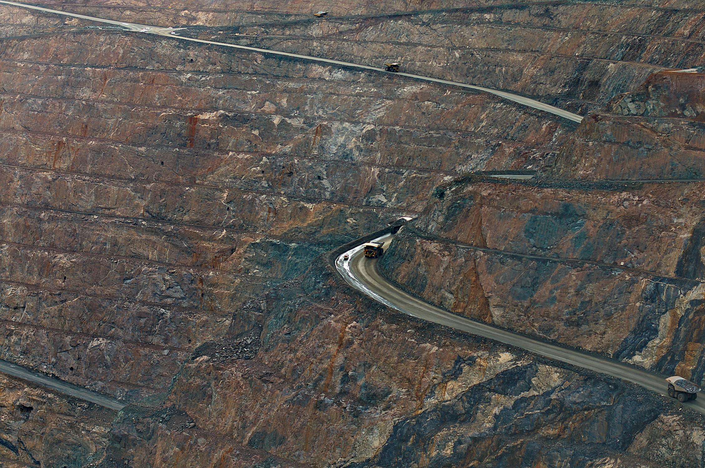 Aerial view of an open pit mine with haul trucks navigating winding access roads