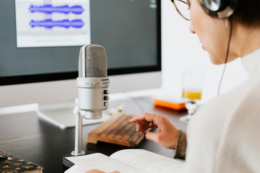 Person wearing headphones speaking into a microphone at a desk