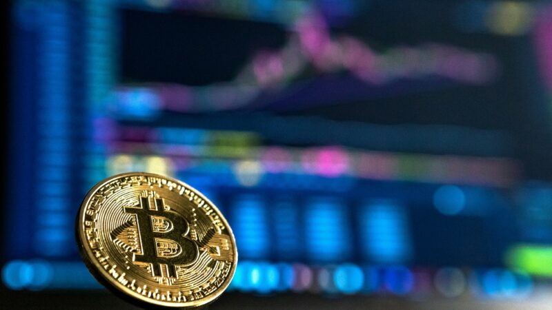 Bull market in crypto: a bronze bull and bear figurine standing back to back over a rising Bitcoin chart
