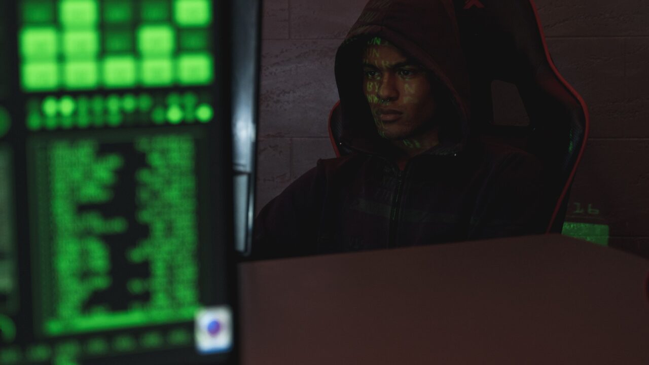 Hooded figure amid green code, representing zero-day security vulnerabilities