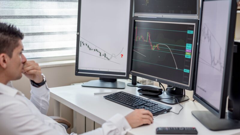 Financial analyst monitoring multiple trading screens and market data