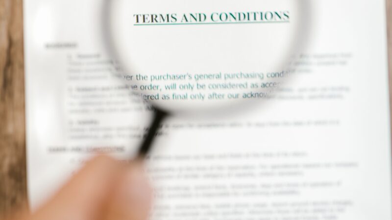 Magnifying glass over terms and conditions, illustrating scrutiny of vague market language