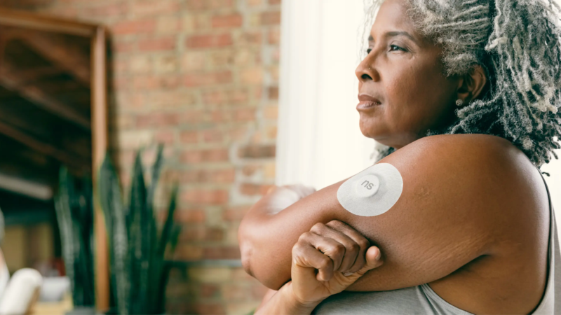 Continuous glucose monitor sensor and phone app showing blood glucose readings.