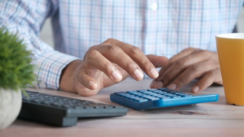 Person using a calculator to review share purchase costs and investment charges
