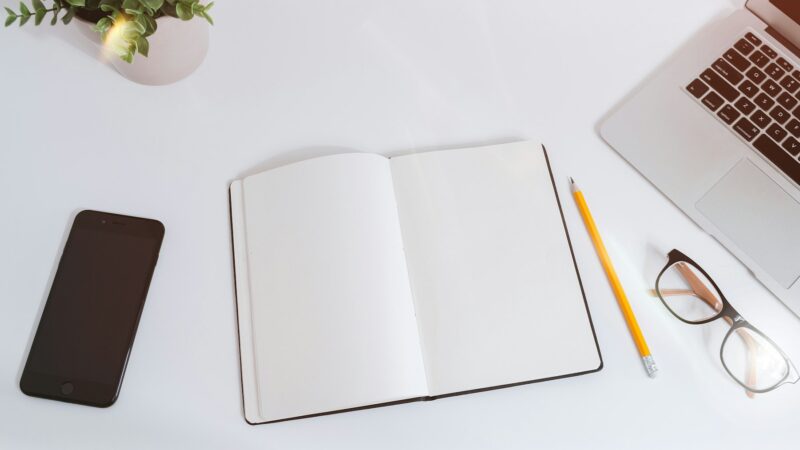 Notebook, labelled sticky notes and a laptop beside model training notes on a white desk