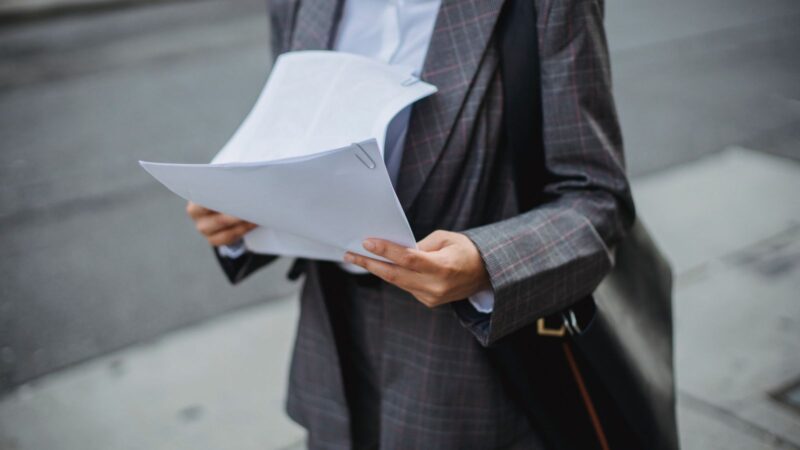 Professional businesswoman reviewing documents outdoors in a city environment.