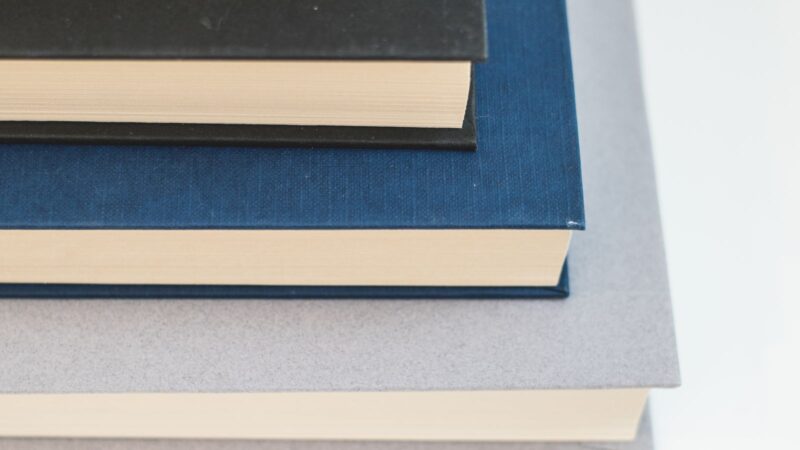 A neatly arranged stack of hardcover books viewed from above, showing diverse colors.