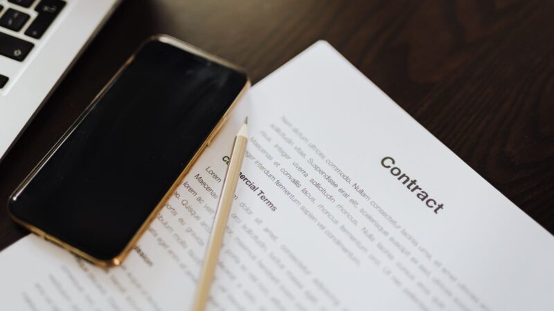 Close-up of a contract document alongside a smartphone and laptop