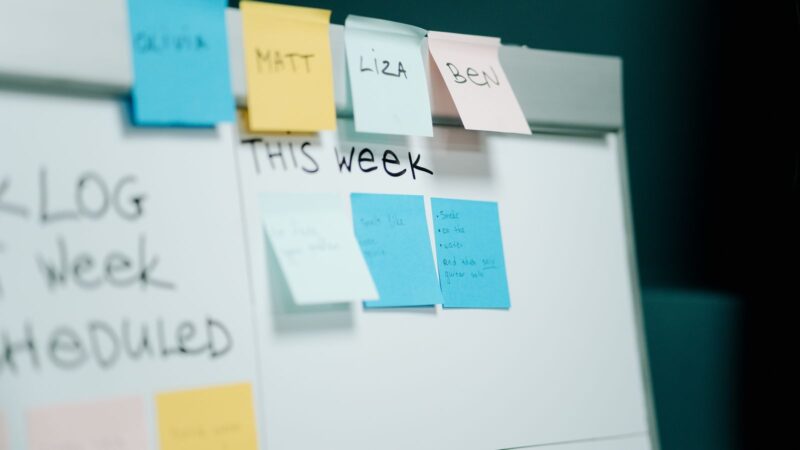 Close-up of a whiteboard with colourful sticky notes arranged for task planning.