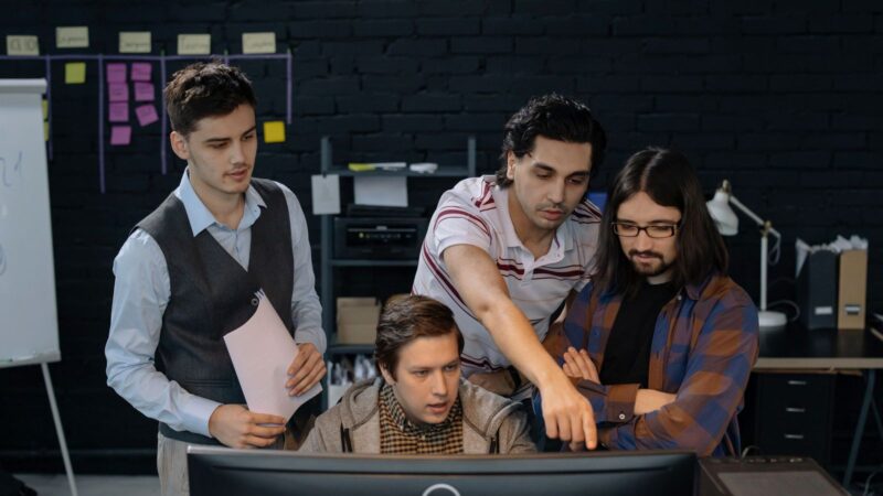 Colleagues seated at a table reviewing information on a computer together.