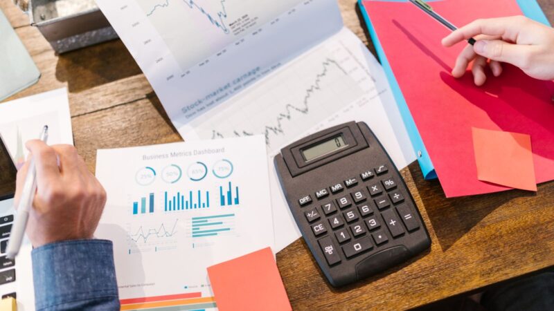 Calculator beside printed charts and financial documents arranged on a table.