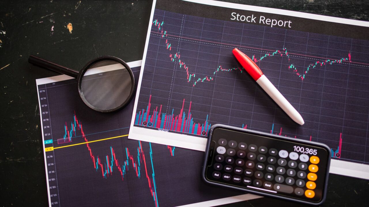 Printed financial report beside a calculator and magnifying glass on a desk.