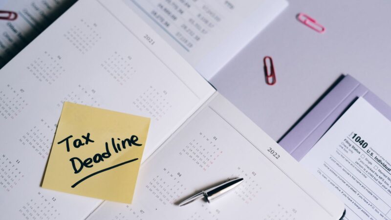 A calendar with a tax deadline note and tax forms, emphasizing organization.